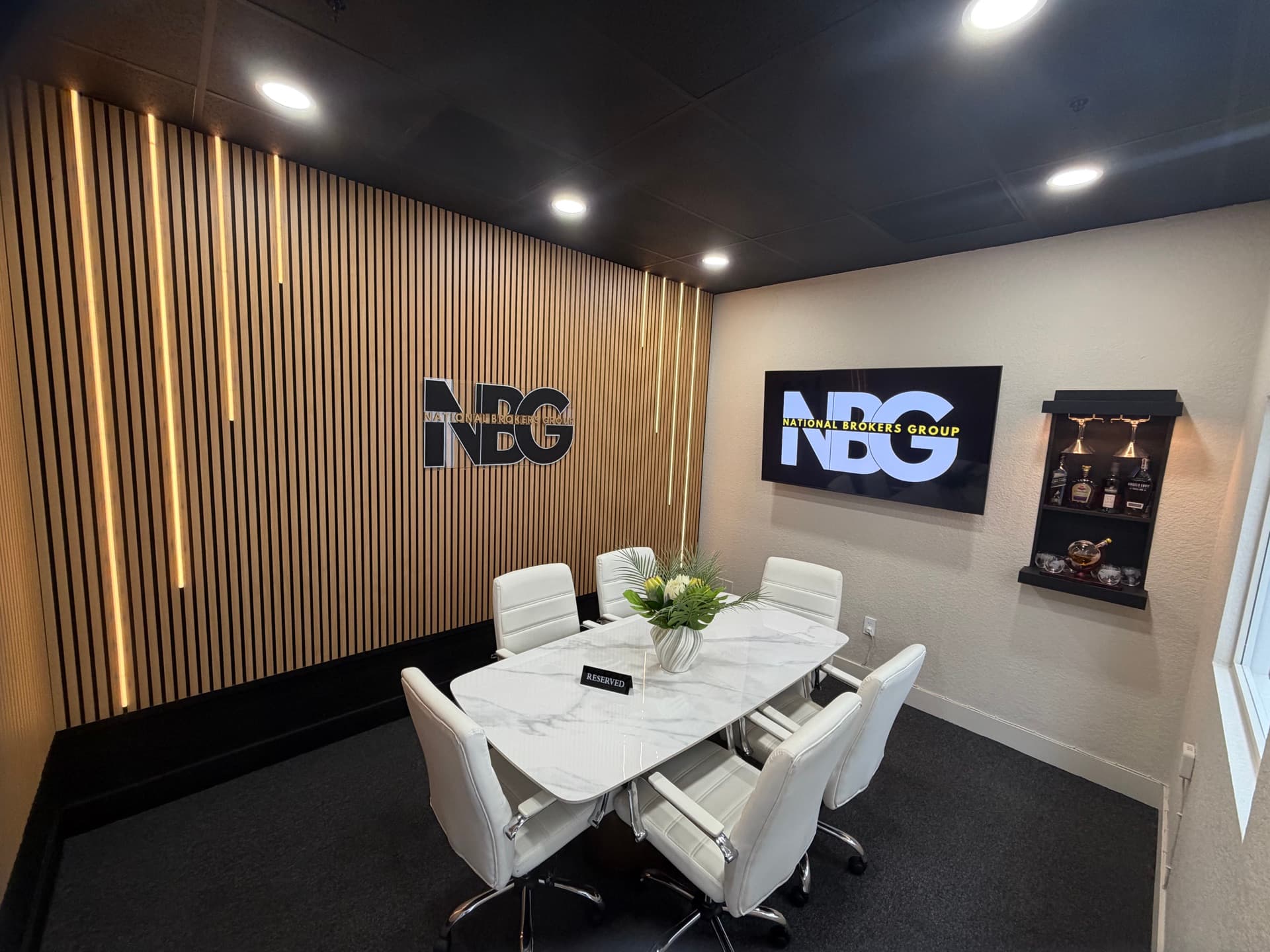 Sala de conferencias ejecutiva de NBG Latino en Doral, Florida — donde recibimos a dueños de empresas latinas para presentar planes de salud grupales · logo NBG iluminado y mesa de mármol