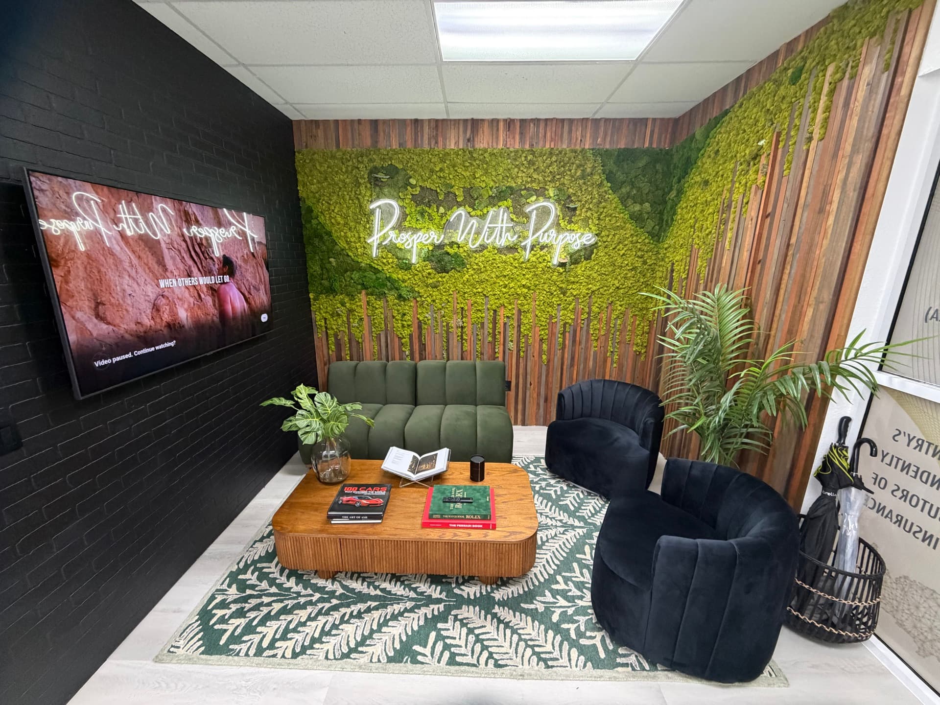 Sala principal de la sede NBG Latino en Doral, Florida — lounge con muro de musgo natural y neón 'Prosper With Purpose'